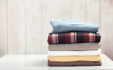 Wall Mural - Folded warm clothing on table empty space background.Stack of colorful clothes,autumn apparel.