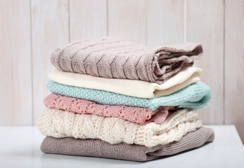 Wall Mural - Stack of knitted textured clothing on table.Colorful winter clothes,warm apparel.Heap of knitwear.