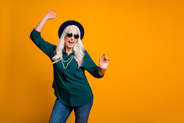 Photo of crazy granny lady young spirit music lover senior party cool look dancing youngster moves wear green shirt sun specs pearls necklace jeans cap isolated yellow color background