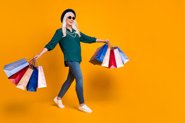 Sticker - Full body profile photo of funky granny lady walk shopping center carry many packs wear green shirt sun specs necklace jeans shoes retro cap isolated bright yellow color background