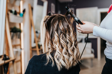 Beautiful hairstyle of young woman after dyeing hair and making highlights in hair salon.