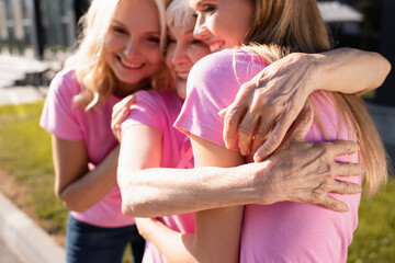 Selective focus of women in pink t-shirts hugging, concept of breast cancer