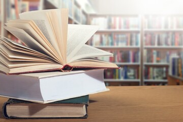 Poster - Open book on stack of books with library background.