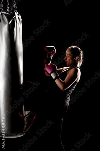 Αφίσα kick fighter girl punching a boxing bag with her leg.