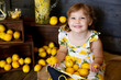 © Rayleigh Leavitt - Young girl sitting with a bunch of lemons in her lap and smiling at the camera.
