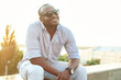 © etonastenka - A dark-skinned guy in sunglasses sits in the park. Portrait of a late 20s black man sitting at the park on a summer day with filtered effect