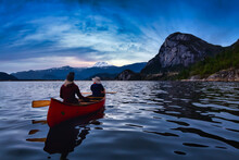 Adventurous People On A Canoe Are Enjoying The Beautiful Canadian Mountain Landscape. Blue Twilight Sunset Artistic Render. Taken In Squamish, North Of Vancouver, British Columbia, Canada.