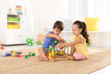 Canvas Print - Cute little children playing with bead maze on floor at home. Educational toy