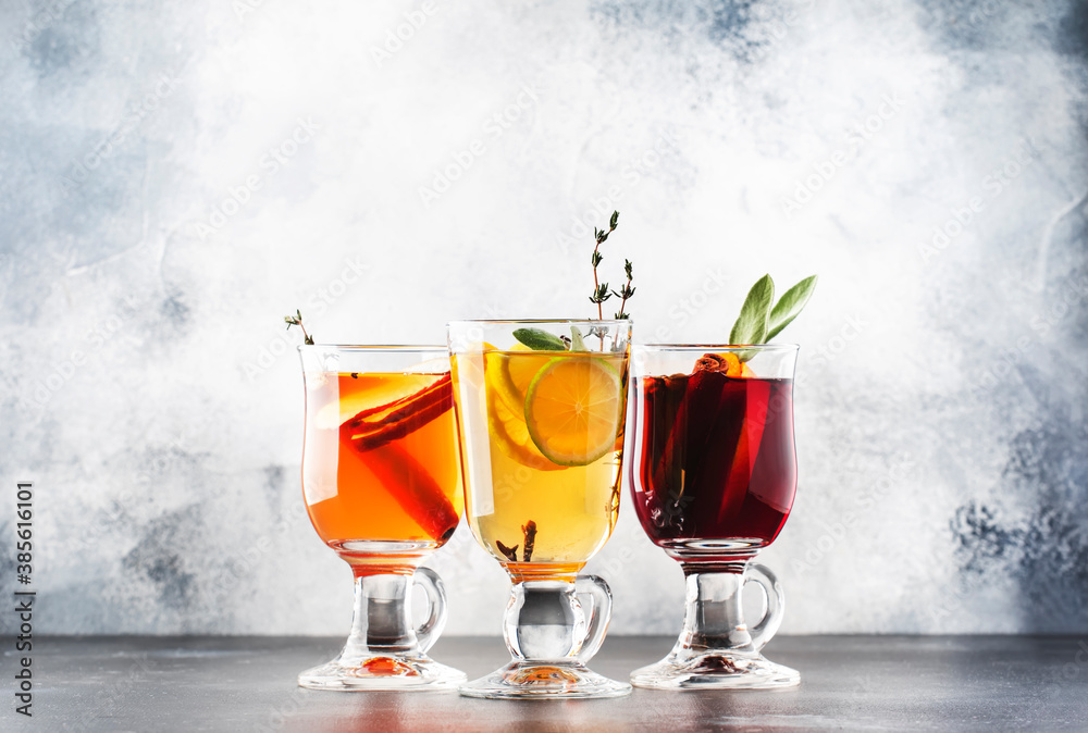Mulled wine from red and white wine and hot mulled cider. Autumn or winter drinks and cocktails in glass mugs with spices and citrus fruit - obrazy, fototapety, plakaty 