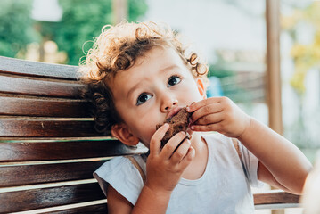 Wall Mural - Little girl savors a cake with a funny face.