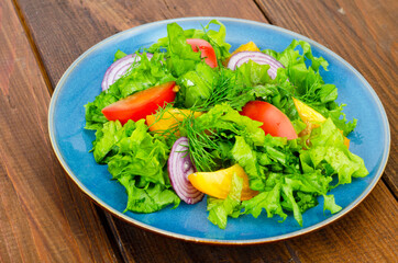 Wall Mural - Light meal of green leaves of lettuce, yellow and red tomatoes, olive oil on wooden table.