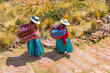 Two Quechua indigenous women in traditional clothing and textile walking down steps, Taquile island, Titicaca Lake, Puno, Peru.
