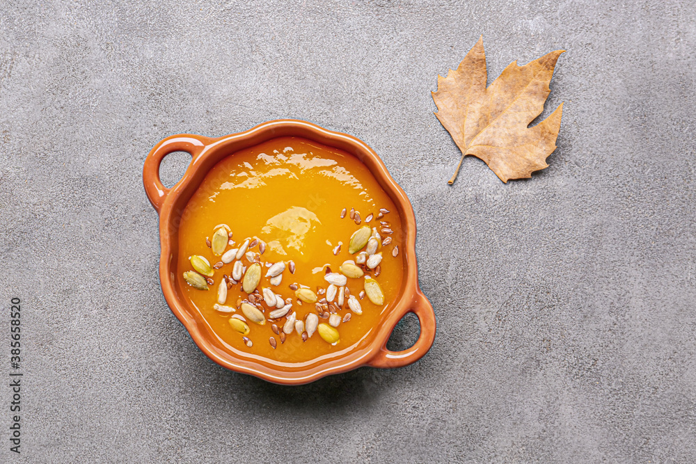 Tasty pumpkin cream soup in pot on grunge background
