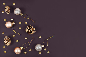 Wall Mural - Elegant Christmas flat lay with golden and silver tree ornament baubles, painted fir cones and small golden snowballs on dark black background with empty copy space