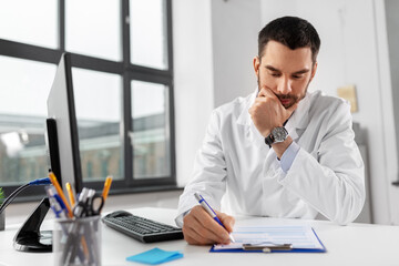 Wall Mural - healthcare, medicine and people concept - stressed male doctor with clipboard at hospital