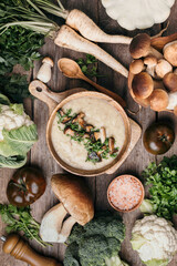 Wall Mural - Homemade vegetarian mushroom soup with fried mushrooms, vegetables, spices, raw boletus edulis mushroom on wooden background. Top view. Copy space. Autumn harvest concept