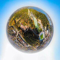 A three dimensional aerial panoramic view of Lahti sports centre with three ski jump towers, in a mini planet panorama style.