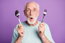 Photo Of Surprised Old Man Hold Fork Spoon Open Mouth Wear Blue T-shirt Isolated Over Violet Color Background