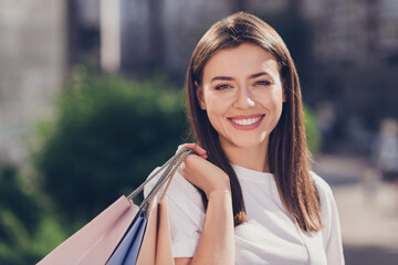 Poster - Photo portrait of girl with shopping bags behind back smiling in park