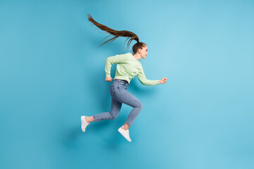 Poster - Full length body size side profile photo of jumping running hurrying girl with long hair ponytail isolated on bright blue color background