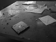Detail From A Desk In An Abandoned Messy Old Office. Floppy Disk And Notes Scattered On The Dusty Table.
