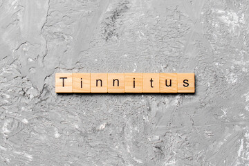 TINNITUS word written on wood block. TINNITUS text on cement table for your desing, concept