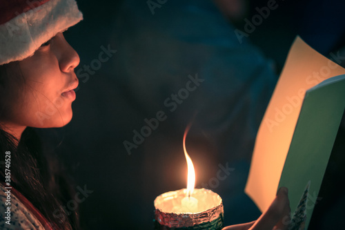 A children singer hands holding candle and book with singing carol song on celebration of christmas day background