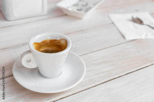 Warm tasty rich italian black espresso coffee cup in white mug on vintage biege wooden rerto style table at cafe or restaurant. Good morning breakfast drink concept. Urban city lifestyle