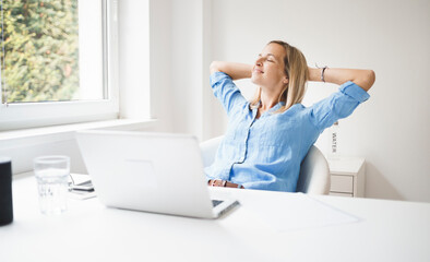 beautiful business woman is relaxing in her homeoffice behind her notebook during corona time