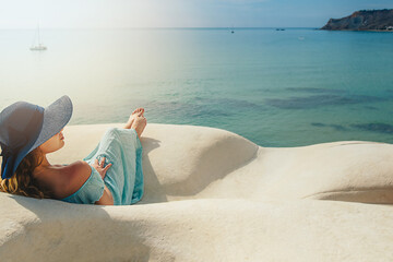 Young woman with hat on the white rocks on the beach Sicily