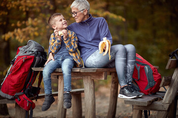 Poster - Grandmother and grandson eating the fruits  on the break of hiking in the forest