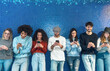 © Alessandro Biascioli - Young people using mobile smartphone while standing against blue background - Youth millennial addicted to new technology social media app concept