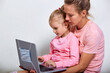 © oleg_ermak - Virus protection concept. Closeup portrait of сute girl 4-5 year old and her mother in pink clothes, showing laptop which medical mask on screen, gray background