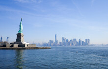 Statue Of Liberty In NY Harbor On Bright Sunny Day With Blue Sky And Manhattan In The Distance