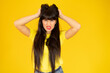 Young pretty woman over yellow background doing nervous gesture