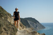© Natalia Tarasova - a woman is engaged in sports walking in the mountains on the coast of the sea