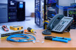 © Anucha - device for network system on table. network gigabit switch, crimping pliers, tester tool and IP Telephone and blur data center room background