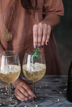 Midsection Of Woman Holding Mint Leaves Over Wineglass While Preparing Cocktail