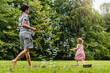 © Daniel Ingold/Westend61 - Brother and sister playing with bubbles in park
