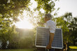 © Gustafsson/Westend61 - Man holding solar panel while pointing towards sunlight in yard