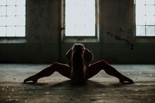 Woman Practicing Yoga While Sitting On Floor At Abandoned Factory