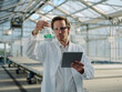 © Joseffson/Westend61 - Scientist with tablet examining liquid in a greenhouse