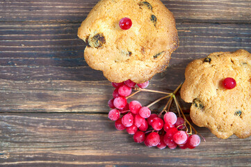 two cupcakes with red berries on a wooden table close up