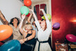 © Eugenio Marongiu/Westend61 - Male and female friends dancing with colorful balloons during party
