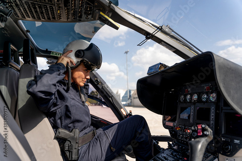 Fotografía Female police pilot wearing helmet while sitting at cockpit in helicopter