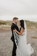 © Sara Monika/Westend61 - Smiling bride and groom looking at each other in field against sky