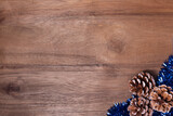 Fototapeta Lawenda - Christmas frame pine cones and blue tinsel on wooden background