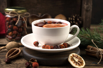 Tea with cinnamon and lemon in a white Cup close - up on a dark background. Side view. The concept of New Year and Christmas.