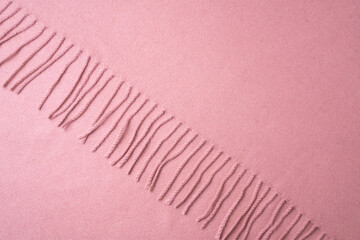 Top view of pink woolen with cotton fabric with fringe - elegant textile background. Winter scarf texture from natural fibers.