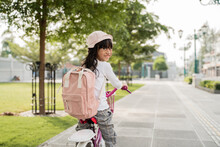 A Portrait Of A Cheerful And Happy Little Girl Riding A Bicycle In The Park Going To School By Herself